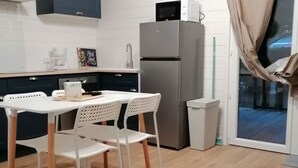 Eine kleine Küche mit Kühlschrank, Mikrowelle und einem Essbereich mit Tisch und Stühlen.