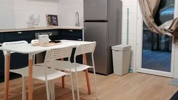 Une cuisine compacte équipée d’un réfrigérateur, d’un four à micro-ondes et d’un coin repas avec une table et des chaises.