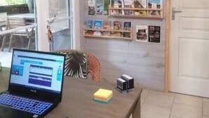 A laptop on a table, a bookshelf with books, and a door. - Chalet air-conditioned pets welcome - 5 guests (Noves)