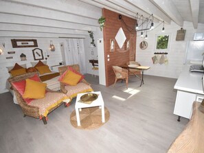 Ein gemütliches Wohnzimmer mit einer Couch, einem kleinen Tisch und einem Essbereich mit einem Stuhl.
