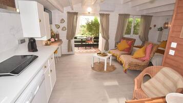 Un espace de vie compact comprenant un coin cuisine, un coin repas et un espace détente avec vue sur l’extérieur.