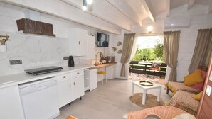 Una cucina moderna con mobili bianchi, una macchina da caffè e un televisore a schermo piatto.