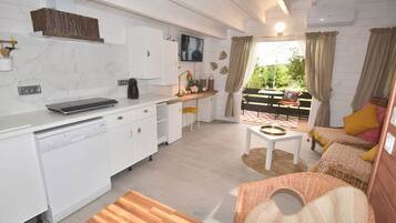 Une cuisine moderne avec des meubles blancs, une machine à café et un téléviseur à écran plat.