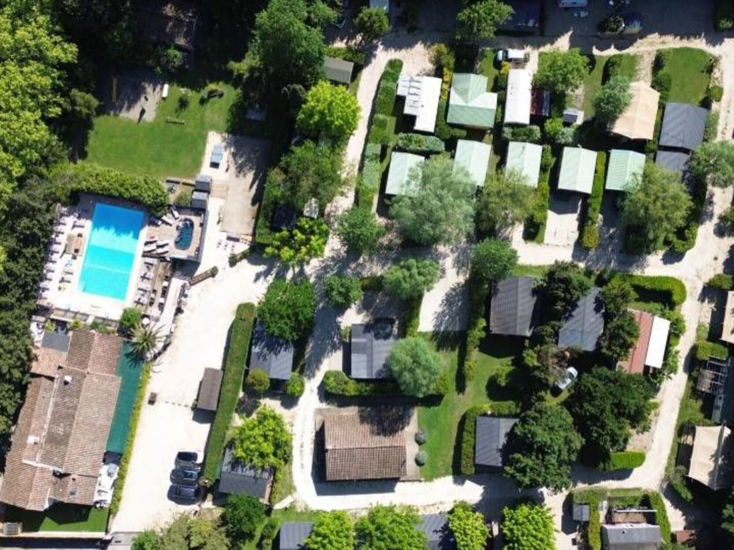 Vue aérienne d’un quartier résidentiel avec des maisons, une piscine et des espaces verts.