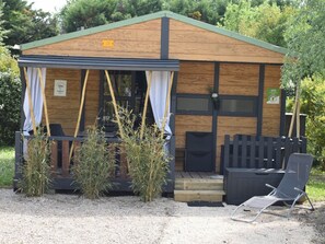 A small wooden cabin with a porch, a chair, and a table. - Cozy chalet with AC - 2 guests (Noves)
