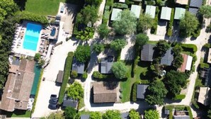 An aerial view of a residential area with houses, a swimming pool, and green spaces.
