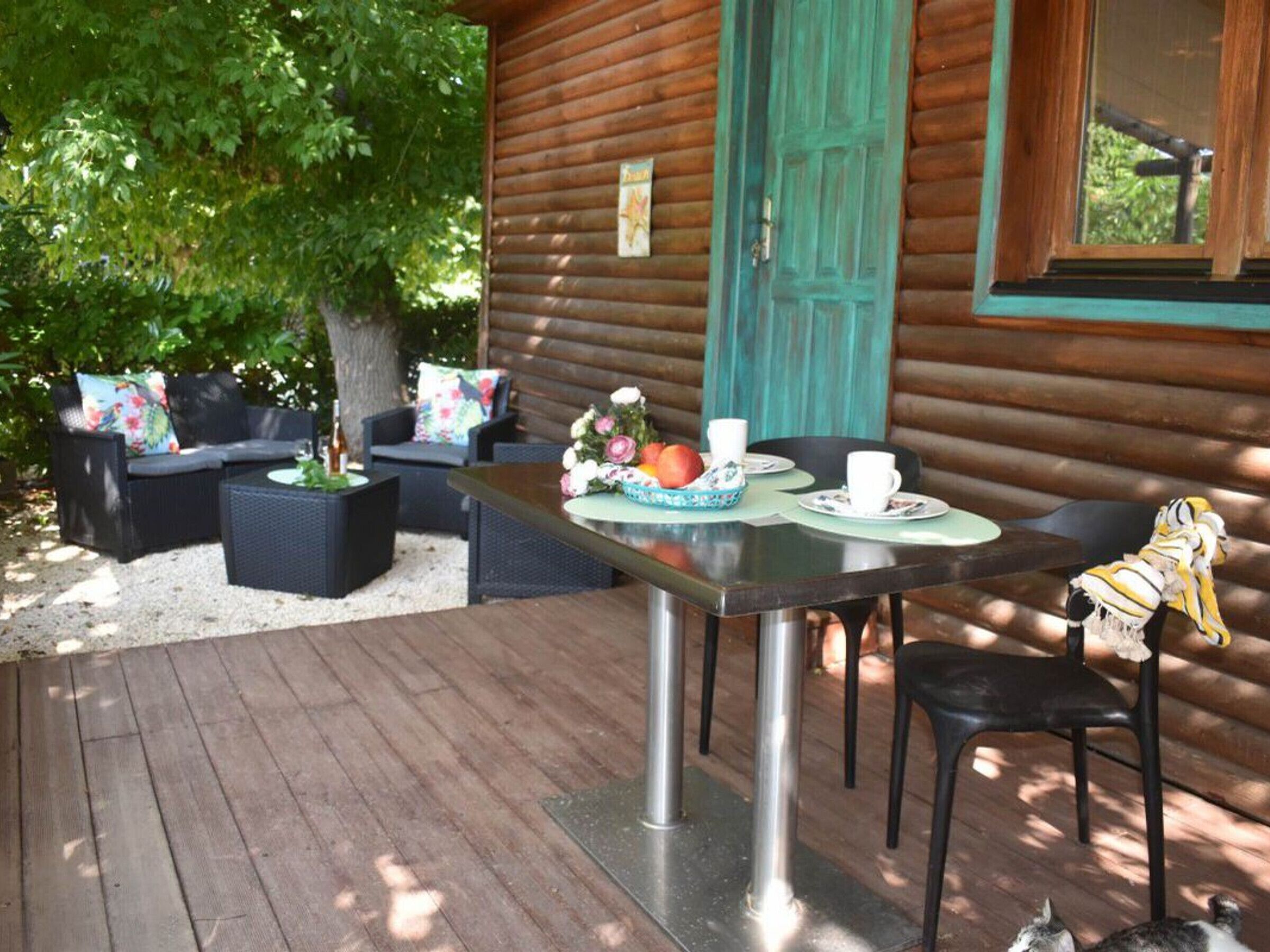 Une cabane en bois dotée d’une terrasse, de meubles de jardin et d’une table dressée pour deux personnes.