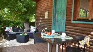 Een houten hut met een terras, zitplaatsen buiten en een tafel gedekt voor twee personen.