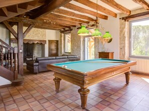 Une table de billard dans une pièce avec un mur en pierre et des poutres en bois.