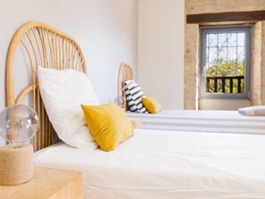A bedroom with a bed, a bedside table, a lamp, and a window with a view.