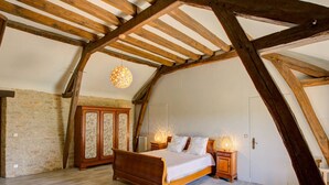 A bedroom with a wooden bed, stone walls, and a sloped ceiling.
