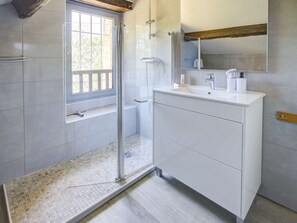 A modern bathroom with a glass shower enclosure, a white vanity, and a large mirror.