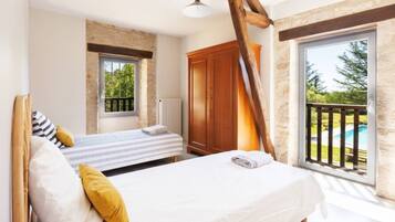 A bedroom with a bed, a window, a wooden wardrobe, and a view of a swimming pool.