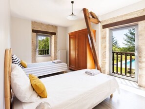 A bedroom with a bed, a window, a wooden wardrobe, and a view of a swimming pool.