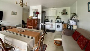 Un espace de vie compact comprenant un coin repas, un canapé, une cuisine équipée et un téléviseur.
