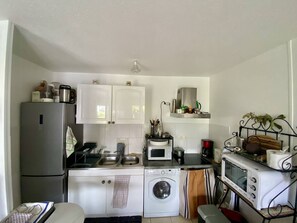 Une cuisine compacte équipée d’un réfrigérateur, d’un four à micro-ondes, d’un four, d’un évier et d’un lave-linge.