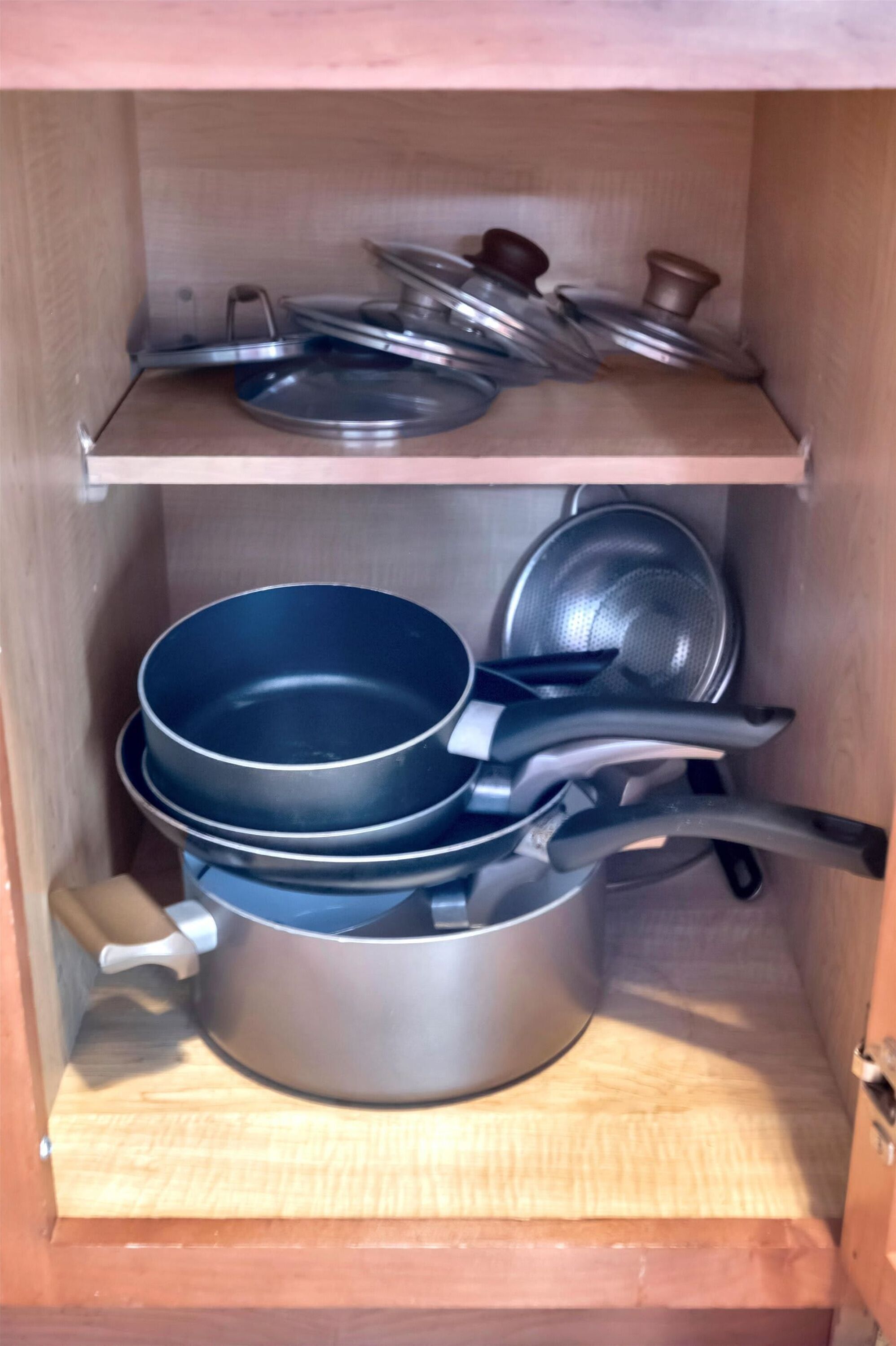 Un meuble de cuisine contenant des casseroles et des poêles à l’intérieur.