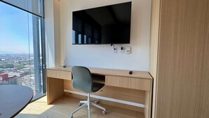 Un espace de bureau moderne comprenant un bureau, une chaise et un téléviseur à écran plat fixé au mur.
