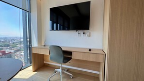Ein moderner Arbeitsraum mit Schreibtisch, Stuhl und einem an der Wand befestigten Flachbildfernseher.