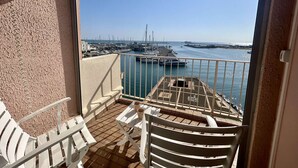 A balcony with a view of a marina, white outdoor furniture, and a tiled floor. - Loft studio with sea view - 4 guests (Cap d'Agde)
