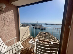A balcony with a view of a marina, white outdoor furniture, and a tiled floor. - Loft studio with sea view - 4 guests (Cap d'Agde)