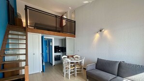A modern apartment with a loft bedroom, a dining area, and a living room with a sofa. - Loft studio with sea view - 4 guests (Cap d'Agde)