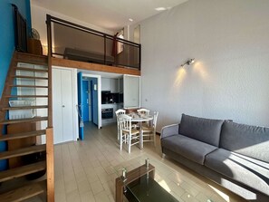A modern apartment with a loft bedroom, a dining area, and a living room with a sofa. - Loft studio with sea view - 4 guests (Cap d'Agde)