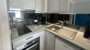 A compact kitchen with a built-in oven, a coffee maker, and a dishwasher. - Loft studio with sea view - 4 guests (Cap d'Agde)