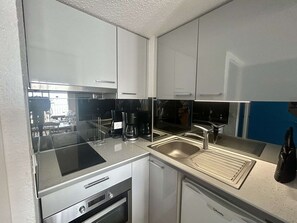 A compact kitchen with a built-in oven, a coffee maker, and a dishwasher. - Loft studio with sea view - 4 guests (Cap d'Agde)