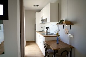 Eine moderne Küche mit Holzarbeitsplatte, weißen Schränken, einem eingebauten Backofen und einer kleinen Essecke mit Tisch und Stühlen.