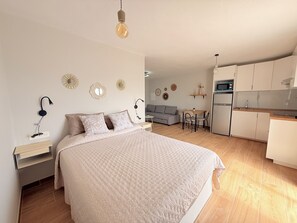 Een slaapkamer met een bed, nachtkastje, lamp en decoratie aan de muur.
