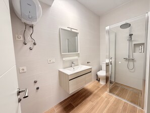 Een moderne badkamer met douche, toilet en wastafel.