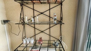 A metal shelf unit with various items including a box labeled 'Plancha,' a glass bowl, and several small containers. - Studio cabin, secure parking - 4 guests (Cap d'Agde)