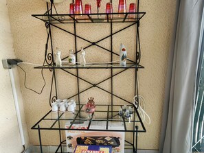 Ein Metallregal mit verschiedenen Gegenständen, darunter eine mit 'Plancha' beschriftete Kiste, eine Glasbowl und mehrere kleine Behälter.