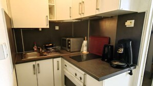 A compact kitchenette with a microwave, toaster, coffee maker, and a small oven. - Studio cabin, secure parking - 4 guests (Cap d'Agde)