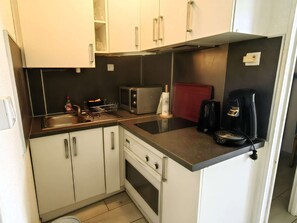 Eine kompakte Küchenzeile mit Mikrowelle, Toaster, Kaffeemaschine und kleinem Backofen.