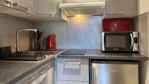 Een moderne keuken met roestvrijstalen apparatuur, een rode waterkoker en een magnetron.