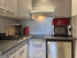 A modern kitchen with stainless steel appliances, a red kettle, and a microwave. - Studio in resort, valley view - 4 guests (Les Orres)