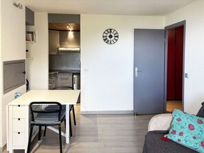 A compact living space with a kitchenette, a dining area, and a door leading to a red room. - Studio in resort, valley view - 4 guests (Les Orres)