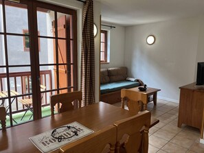 A cozy room with a wooden dining table, a sofa, and a television. - Duplex apartment in the mountains - 6 guests (Cauterets)