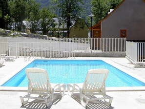 A rectangular pool with two white lounge chairs facing each other, surrounded by a white fence, with a mountainous backdrop. - Duplex apartment in the mountains - 6 guests (Cauterets)