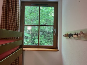 A room with a window, a bed, and a wall-mounted shelf with figurines. - Duplex apartment in the mountains - 6 guests (Cauterets)