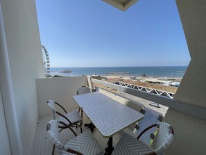 Un balcón con mesa y sillas, con vista a una playa y un muelle.