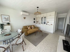 Ein modernes Wohnzimmer mit einer Couch, einem Esstisch, Stühlen und einer Küchenzeile.