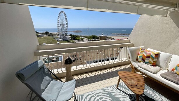 Ein Balkon mit Blick auf ein Riesenrad, einen Strand und einen klaren Himmel.