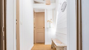 Un pasillo con un banco, una puerta y un estante en la pared con flores.