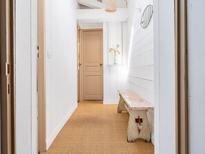 Ein Flur mit einer Bank, einer Tür und einem an der Wand befestigten Regal mit Blumen.