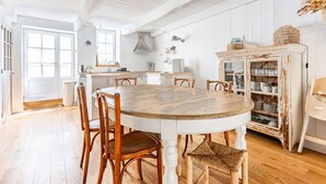 Una cocina amplia con una mesa y sillas de madera, un armario blanco y un ventanal grande.