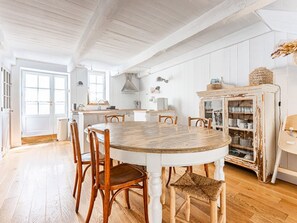 Eine geräumige Küche mit einem Holztisch und Stühlen, einem weißen Schrank und einem großen Fenster.