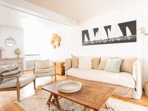 Ein Wohnzimmer mit einer Couch, Sesseln, einem Couchtisch, einem Globus und einem an der Wand hängenden Kunstwerk.